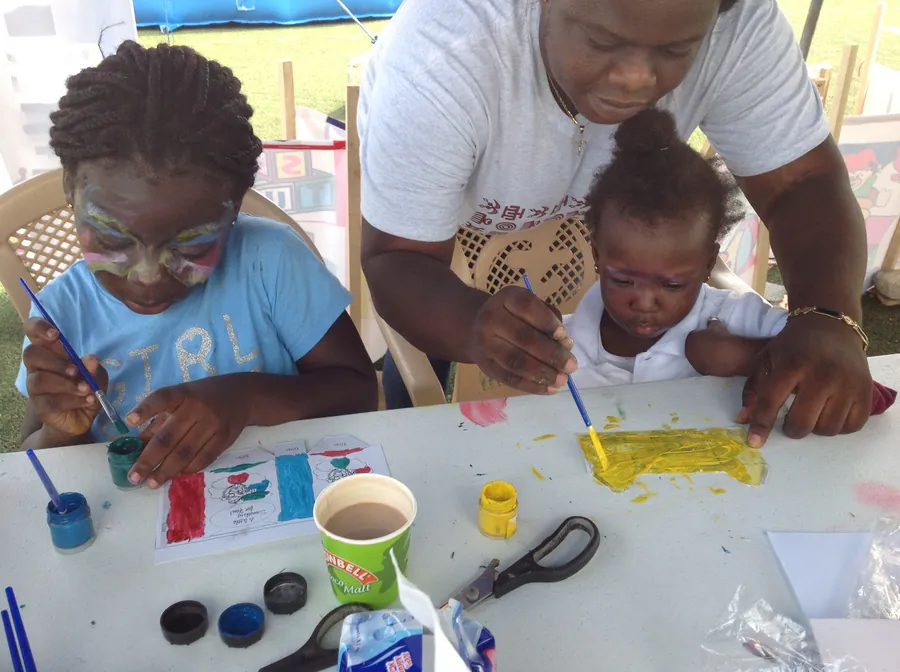 An adult guiding a young child as she paints at an Eazi Education workshop