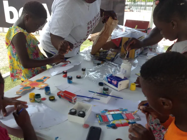 Children painting and crafting at an Eazi Education exhibition table